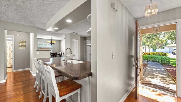 Una cocina moderna con una isla central, taburetes blancos y un área de comedor.