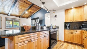 A modern kitchen with wooden cabinets, granite countertops, and stainless steel appliances. - Steps to Trails & Minutes to Heavenly + Firepit | Bluewood Cabin by AvantStay (South Lake Tahoe)