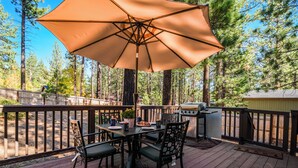 A deck with a table, chairs, an umbrella, and a grill. - Steps to Trails & Minutes to Heavenly + Firepit | Bluewood Cabin by AvantStay (South Lake Tahoe)