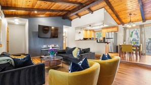 A modern living room with a sofa, yellow armchairs, and a coffee table. A flat-screen TV is mounted on the wall. - Steps to Trails & Minutes to Heavenly + Firepit | Bluewood Cabin by AvantStay (South Lake Tahoe)
