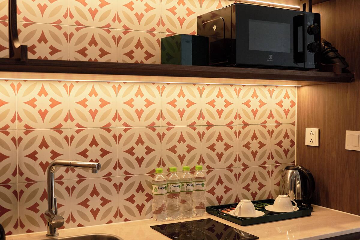 A modern kitchen with a stainless steel sink, a microwave, and a kettle on the countertop.