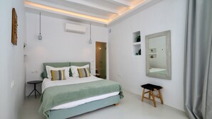 Une chambre à coucher avec un lit, une table de chevet, un miroir et un petit tabouret.