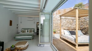 Une chambre moderne avec un lit, un canapé et une porte en verre donnant sur un espace extérieur doté d’une structure en bois.