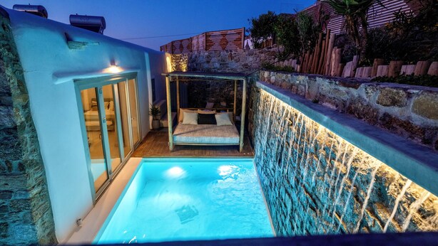 Une petite piscine extérieure dotée d’une terrasse en bois et d’un mur en pierre.