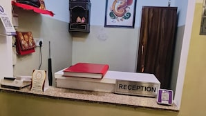 A reception area with a reception desk, a framed picture of a deity, and a red book on the counter. - Roomshala Hotel Mannat (New Delhi)