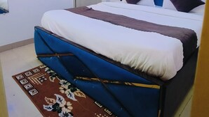 A bedroom with a bed, a ceiling fan, an air conditioner, and a floral rug. - Roomshala Hotel Mannat (New Delhi)