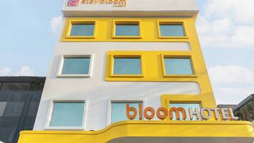 Un hotel con fachada amarilla y blanca, múltiples ventanas y el nombre 'bloomhotel' exhibido con destaque.