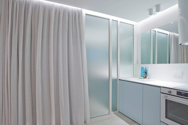A modern kitchen with a built-in oven, a white countertop, and a frosted glass door.