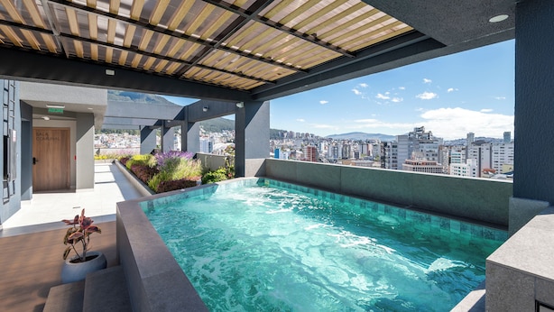 A rooftop pool with a city view, a covered seating area, and a sign for "SALA COMUNAL". - Edificio Efyra by Host Ecuador (Quito)