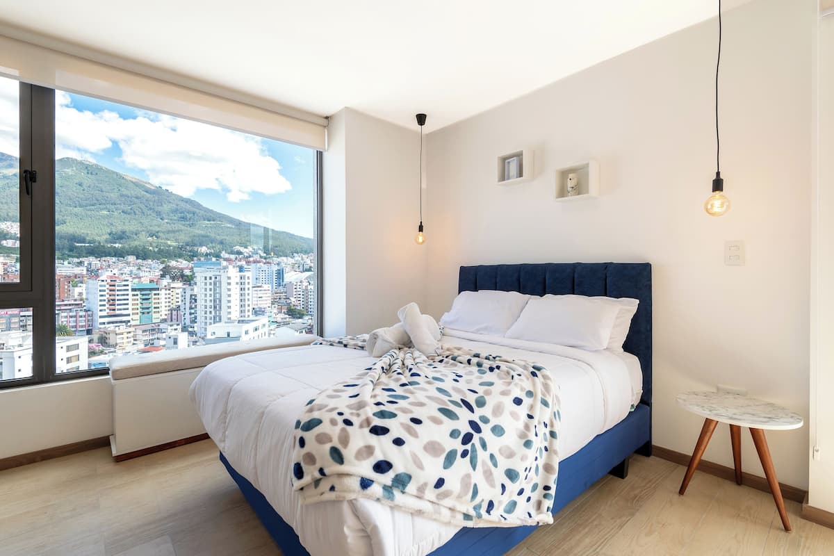 Una camera da letto moderna con un letto grande, vista sulla città e un tavolino.