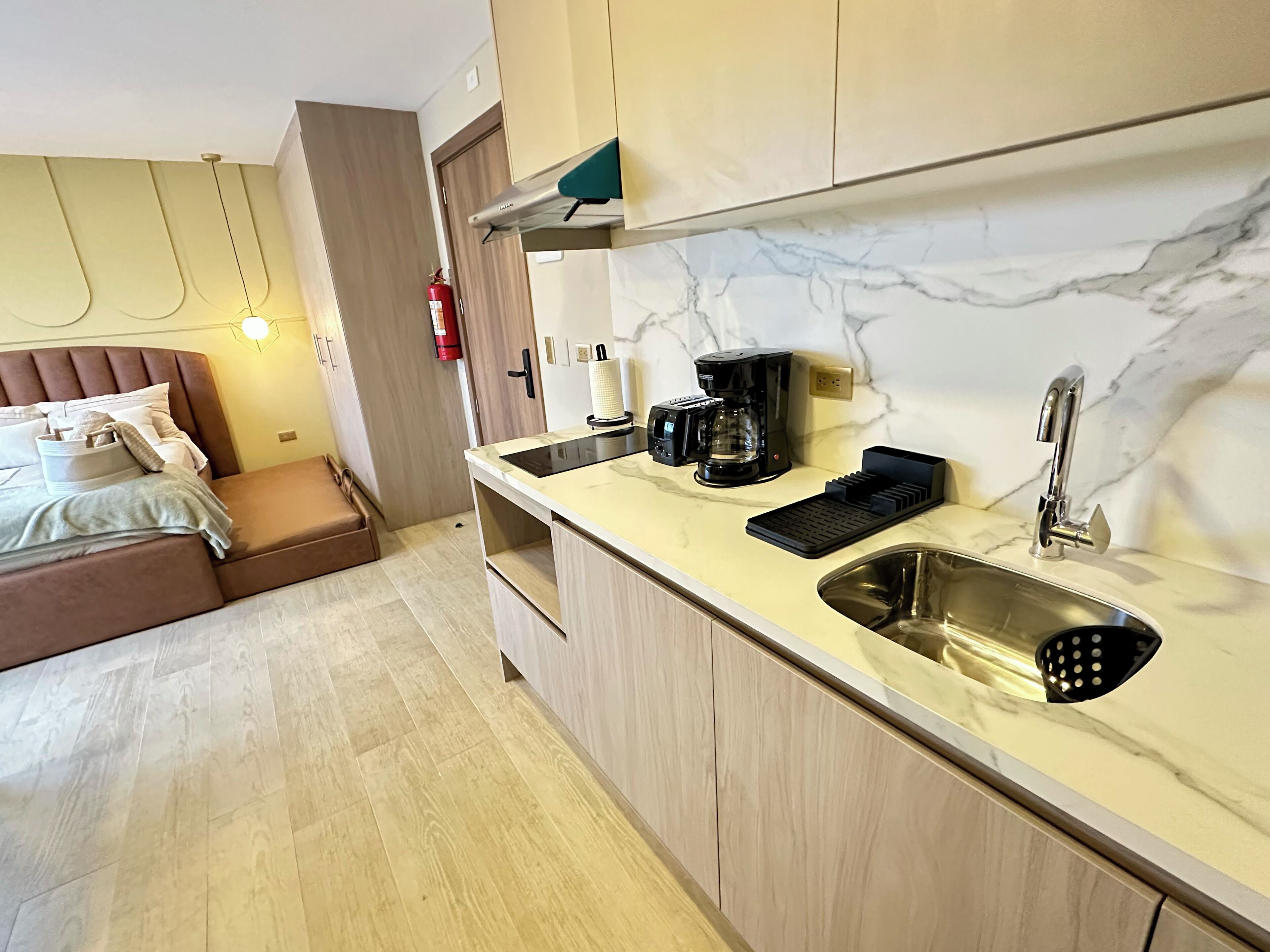 A modern kitchen with a marble countertop, a coffee maker, and a sink.
