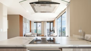 A modern kitchen with a large island, stainless steel appliances, and a city view through large windows. - Edificio Efyra by Host Ecuador (Quito)