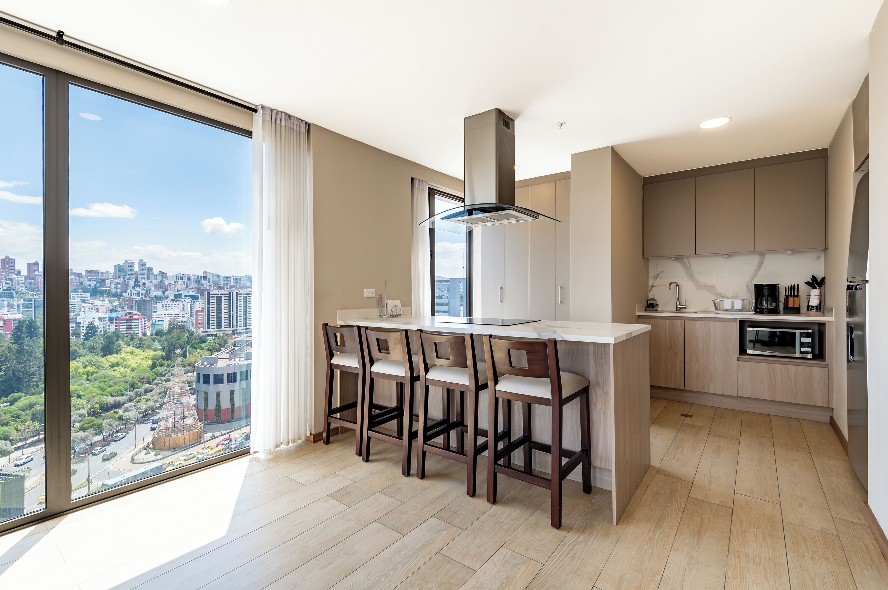 Eine moderne Küche mit großem Fenster, einer zentralen Kochinsel mit Barhocker und eingebauten Geräten.
