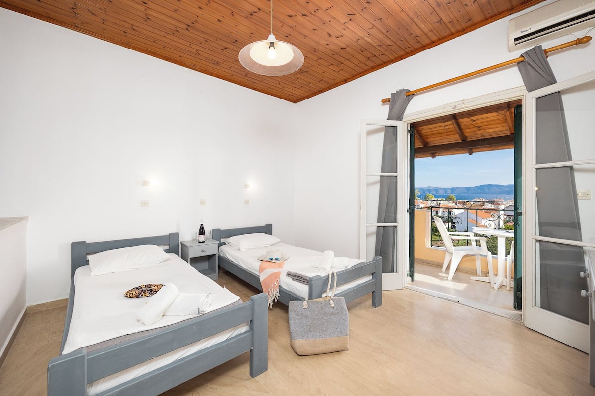 Une chambre avec deux lits, un balcon avec vue et un ventilateur de plafond.