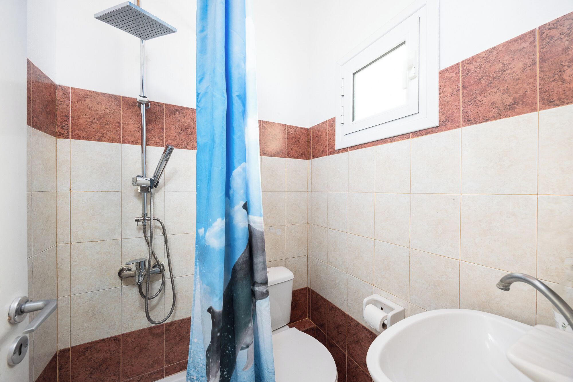 A bathroom with a shower, toilet, and sink.