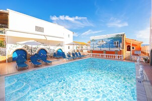 Una piscina al aire libre, sombrillas, tumbonas