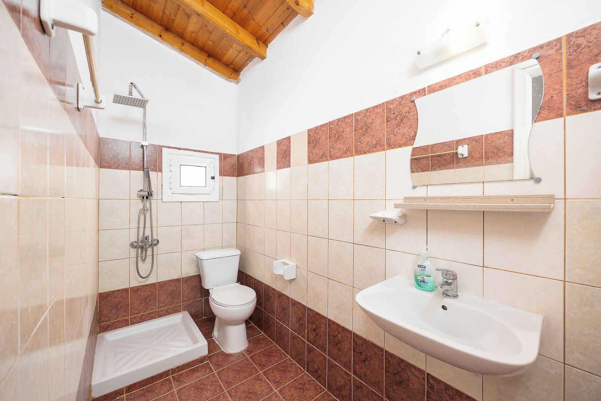 A bathroom with a shower, toilet, sink, and a mirror.