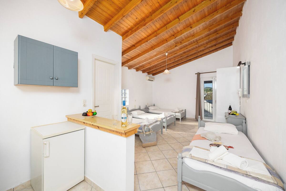 Une chambre d’hôtel de taille réduite, comprenant deux lits, une petite kitchenette et une salle de bain.