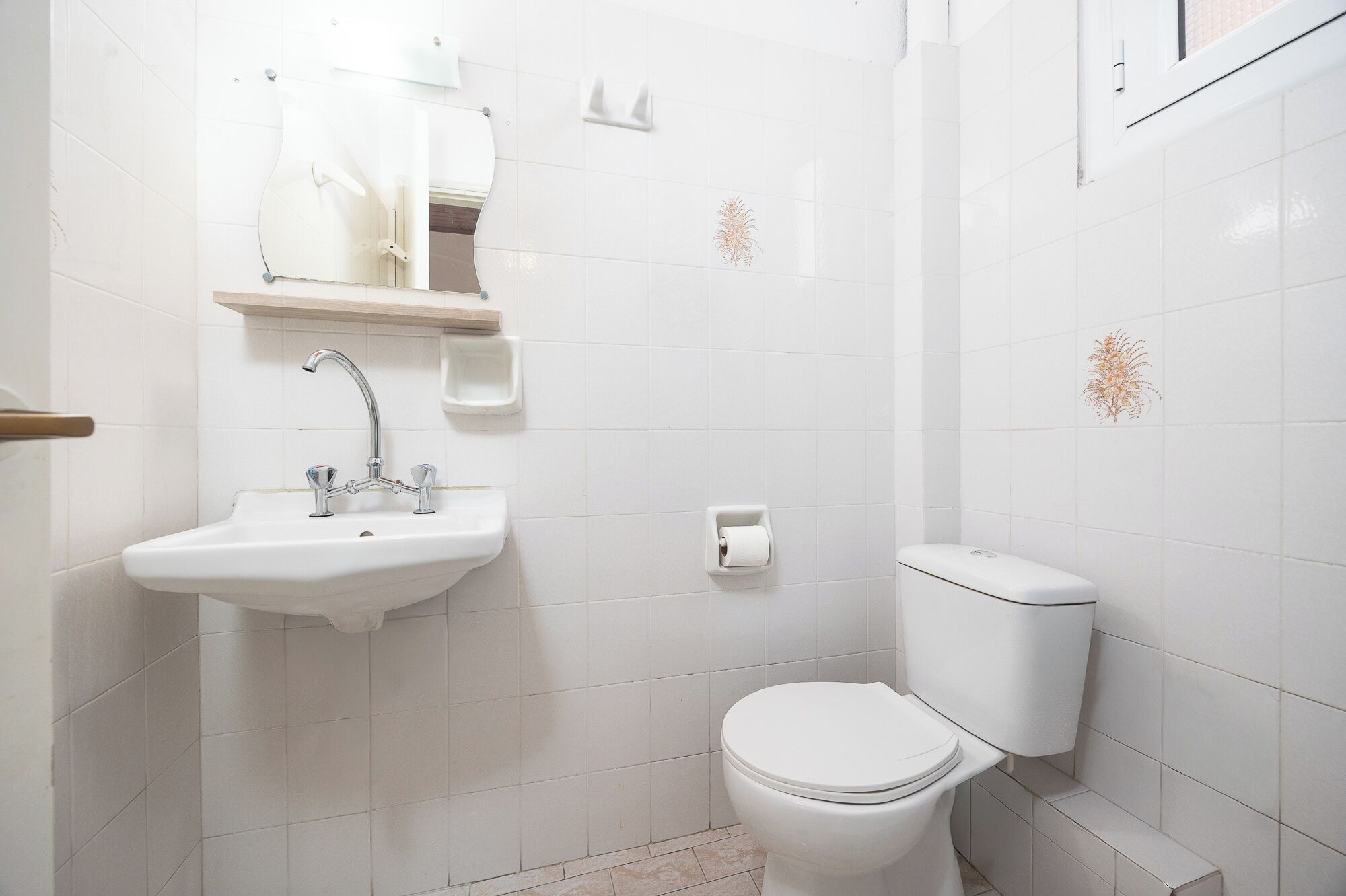 Et badeværelse med en hvid vask, toilet og et spejl.