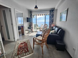 Un salon avec un canapé, des fauteuils, un téléviseur et un balcon offrant une vue agréable.