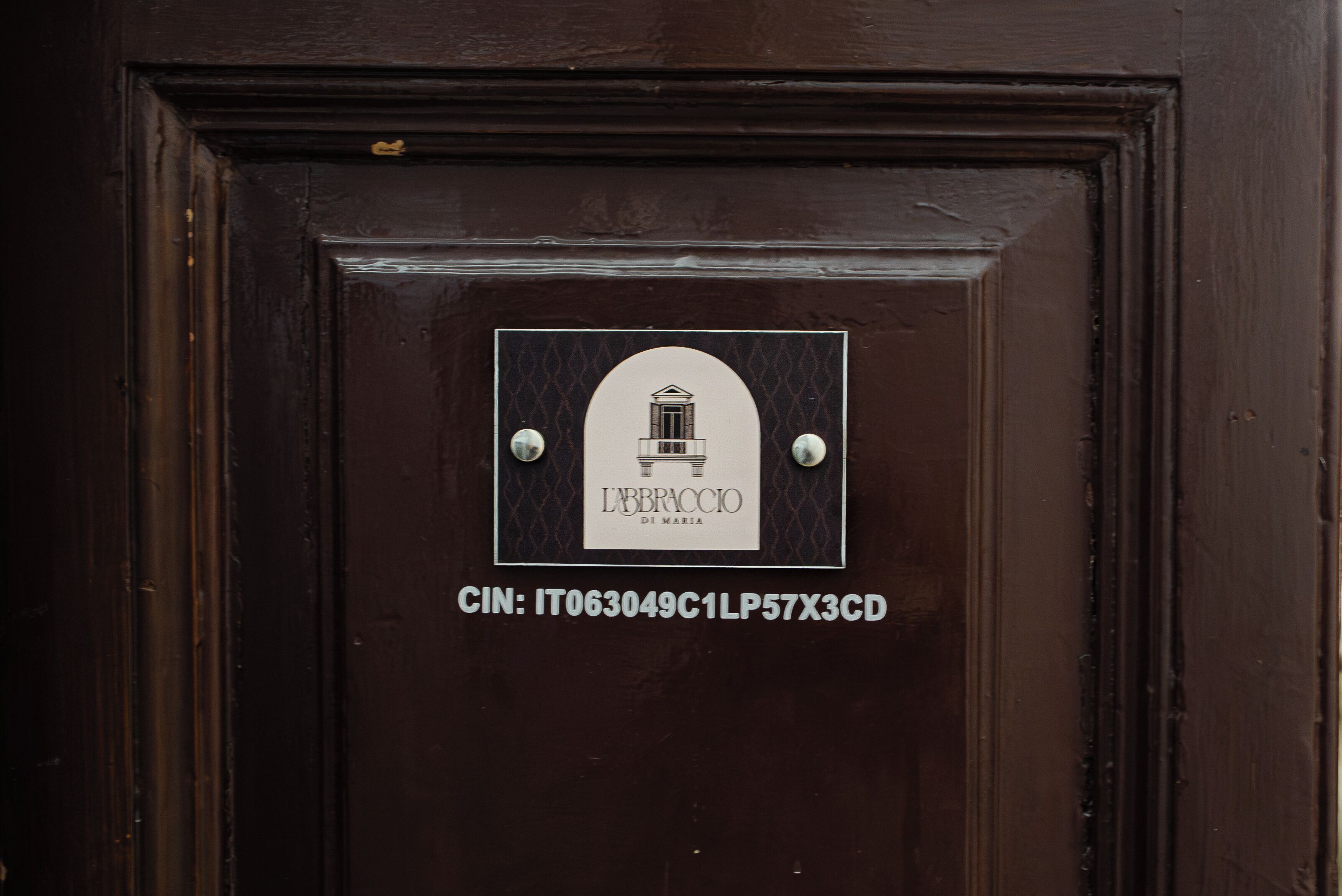 A dark wooden door with a plaque displaying a logo and a CIN code.