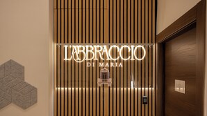 A hotel entrance with a vertical wooden panel design and a sign reading "LABBRACCI DI MARIA". - l'abbraccio di Maria (Naples)