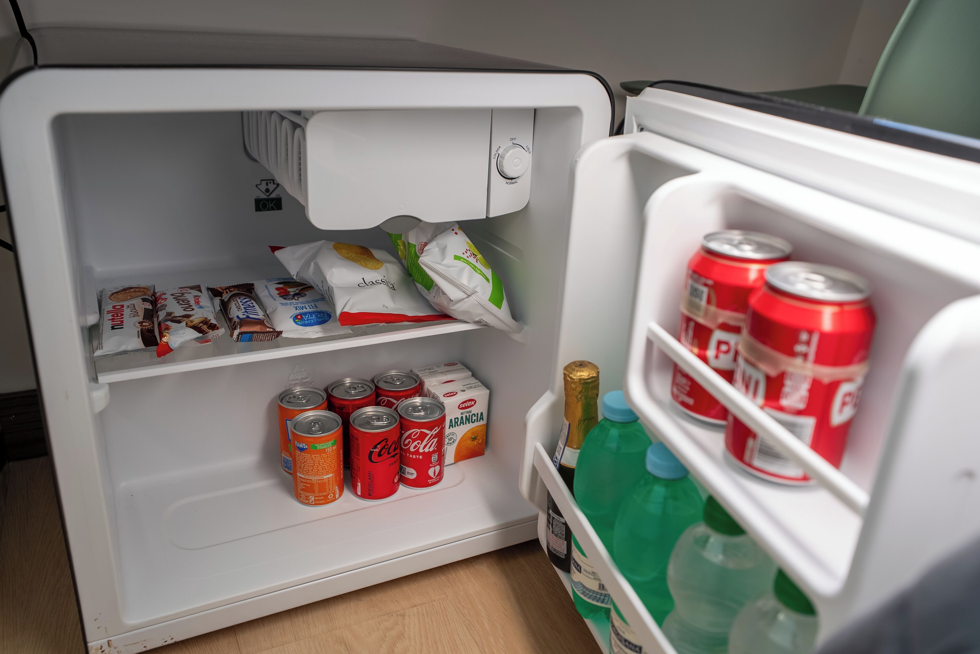 Un frigorifero con bevande, lattine e prodotti alimentari confezionati.