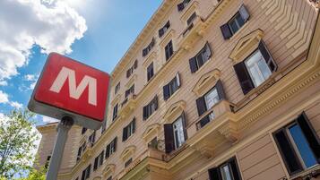 Un edificio con un llamativo letrero rojo en forma de 'M', varias ventanas y un cielo despejado.
