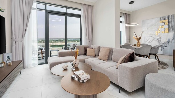 Una sala de estar moderna con un sofá grande, una mesa de centro y un comedor con candelabro.