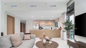 Una sala de estar moderna con un sofá, una mesa de centro y un televisor sobre un mueble.