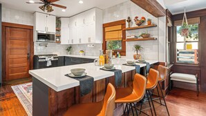 A modern kitchen with white cabinets, a large island, and orange bar stools. - 2 Side-by-Side San Diego Homes w/ Shared Backyard, Firepit & BBQ (San Diego)
