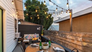 An outdoor patio with a round wooden table set for dining, surrounded by wooden chairs. - 2 Side-by-Side San Diego Homes w/ Shared Backyard, Firepit & BBQ (San Diego)