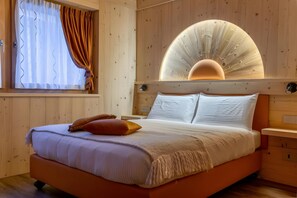 Une pièce aux murs lambrissés, comprenant un lit, un grand luminaire circulaire et une fenêtre avec des rideaux.