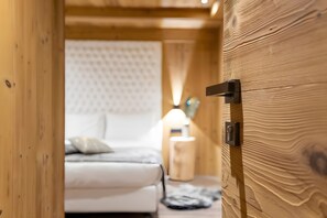 A wooden interior with a bed, a nightstand, and a lamp.