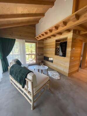 A cozy room with a bed, a small table, a TV, and a window with curtains.