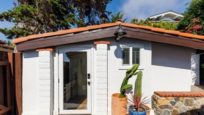 Una casa con pareti bianche, un tetto marrone e un muro in pietra.