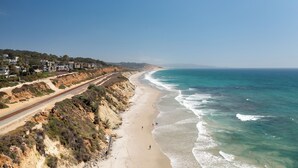 Una strada costiera con una spiaggia e l'oceano da un lato, e una zona residenziale con case dall'altro.