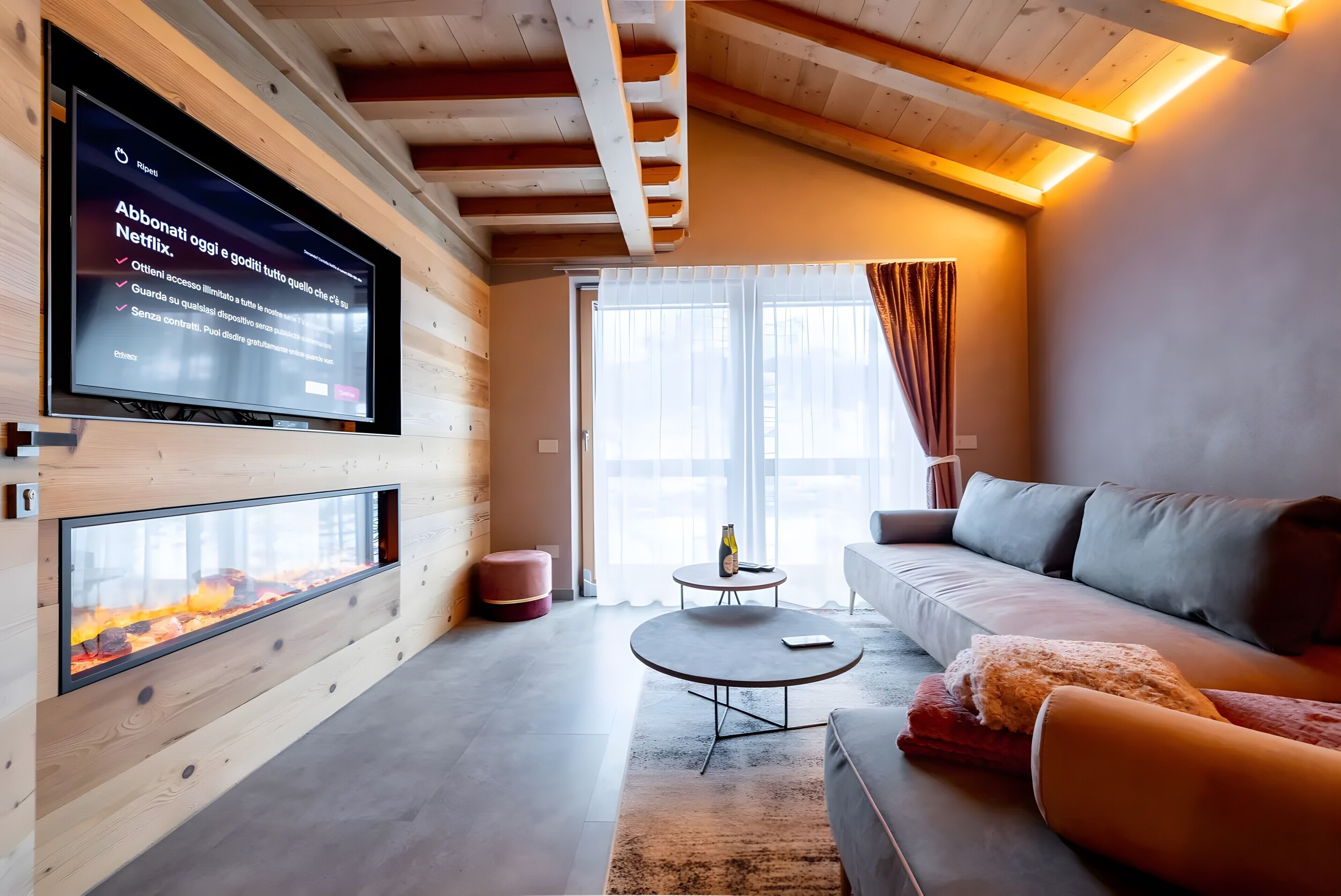 Een moderne woonkamer met een open haard, een grote flatscreen televisie, een bank en een ronde salontafel.