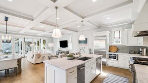 A spacious kitchen with a central island, white cabinetry, stainless steel appliances, and pendant lighting. - WaterColor! HUGE Private Pool, Carriage House, Bikes, & 6-Seater LSV/Golf Cart! (Santa Rosa Beach)