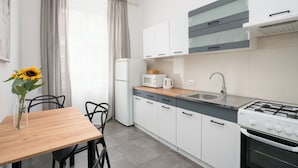 Une cuisine moderne avec des meubles blancs, une cuisinière à gaz, un four à micro-ondes et un évier.