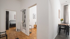 Un intérieur moderne avec un plancher en bois, un coin repas comprenant une table et des chaises, et un lit en arrière-plan.