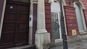Un bâtiment jaune avec une porte rouge et des colonnes blanches.