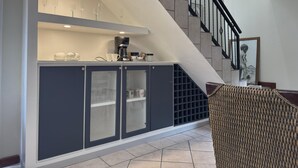 Een moderne keuken met een ingebouwde koffiehoek, een trap en een rieten stoel.