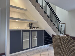 Una cocina moderna con una estación de café integrada, una escalera y una silla de mimbre.