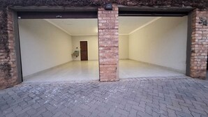 A spacious, empty room with a tiled floor and a brick pillar.