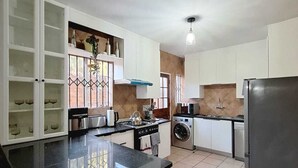 Een moderne keuken met witte kasten, een zwart aanrecht, een roestvrijstalen koelkast en een ingebouwde wasmachine.