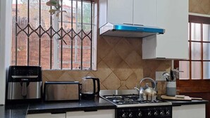 A kitchen with white cabinets, a stove, a toaster, and a window with decorative iron bars.