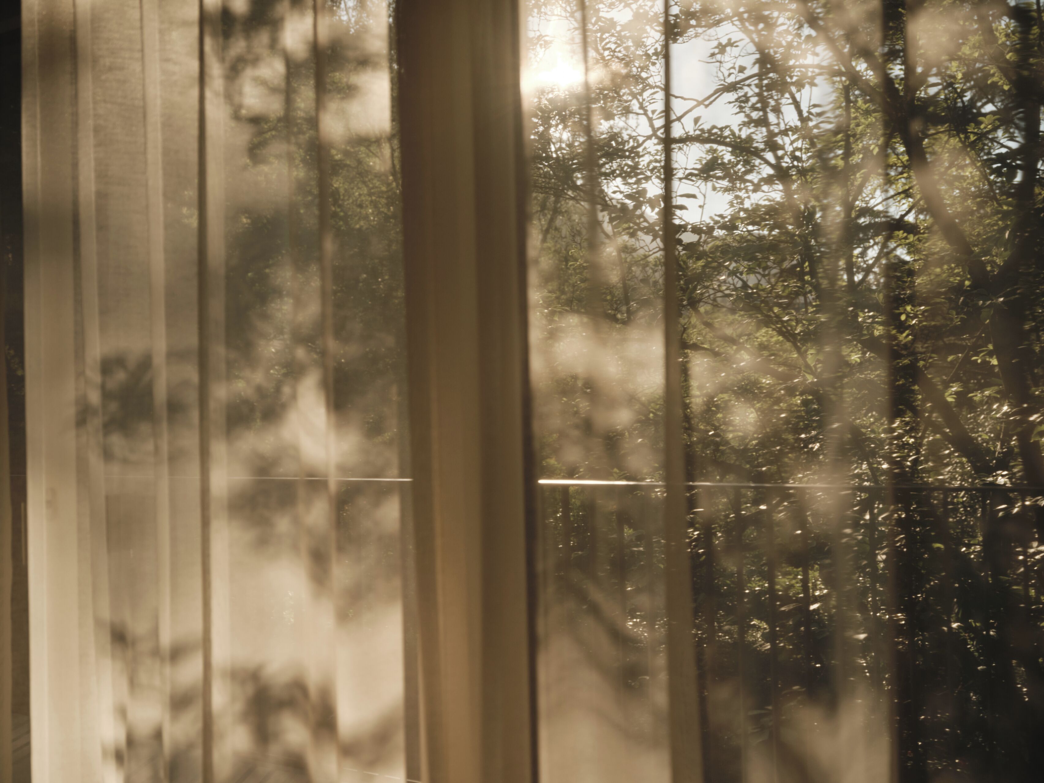Una ventana con persianas verticales entreabiertas, dejando que la luz del sol ilumine el interior.