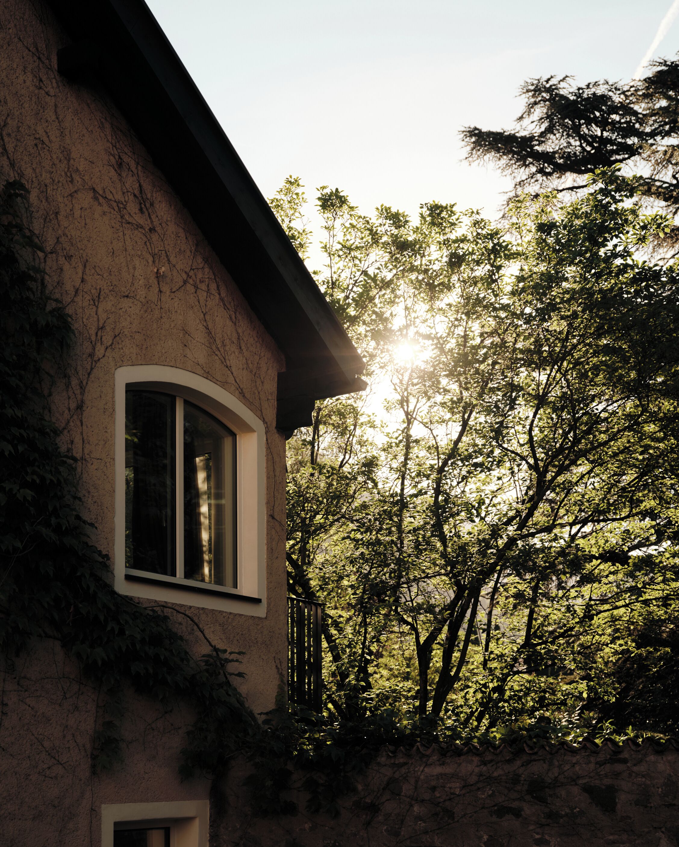 A house with a window, surrounded by trees and a clear sky.