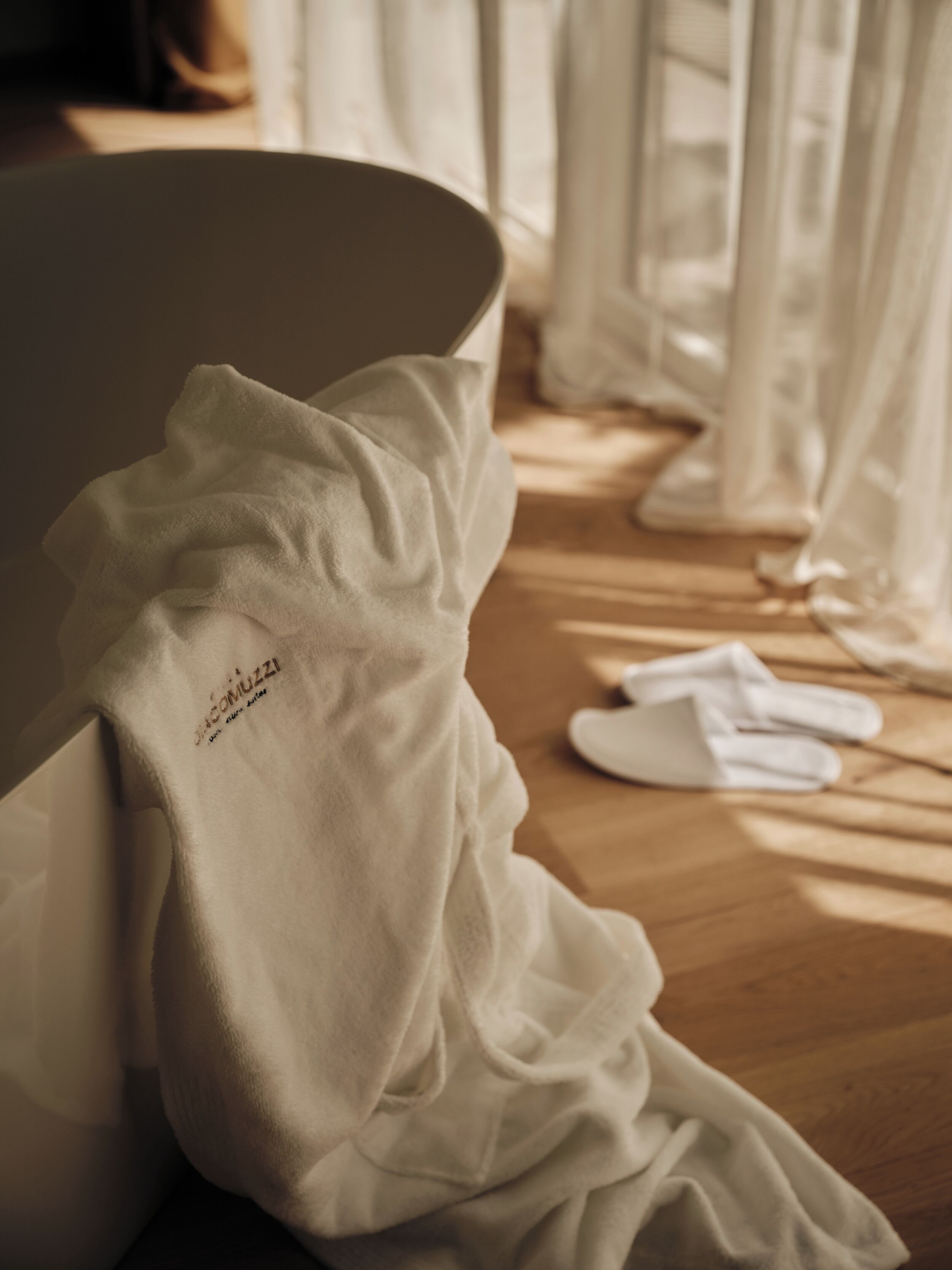 Une pièce avec un plancher en bois, une chaise blanche et une table blanche recouverte d’une nappe blanche.